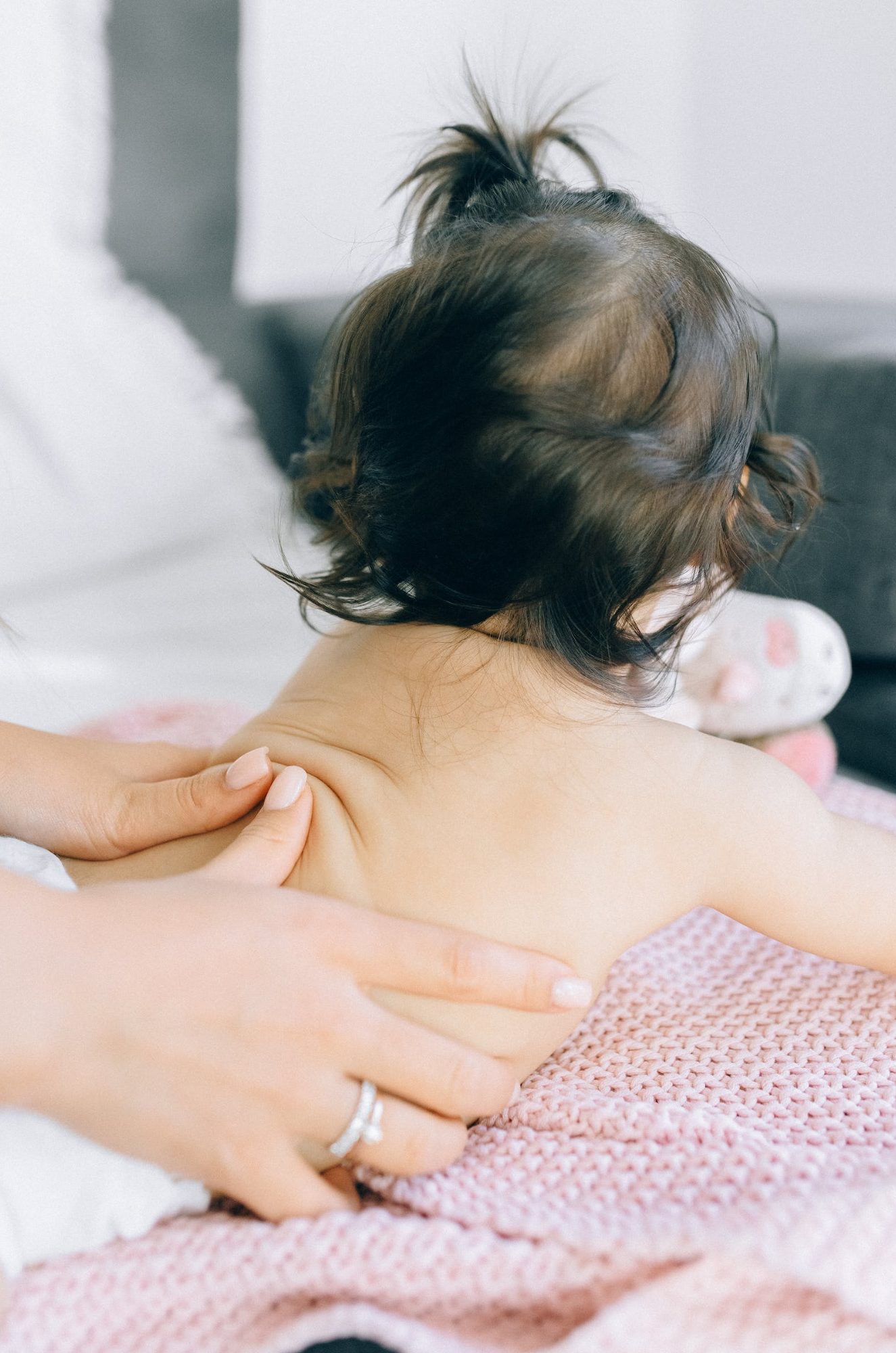 Des mains de parents massent le dos de son bébé